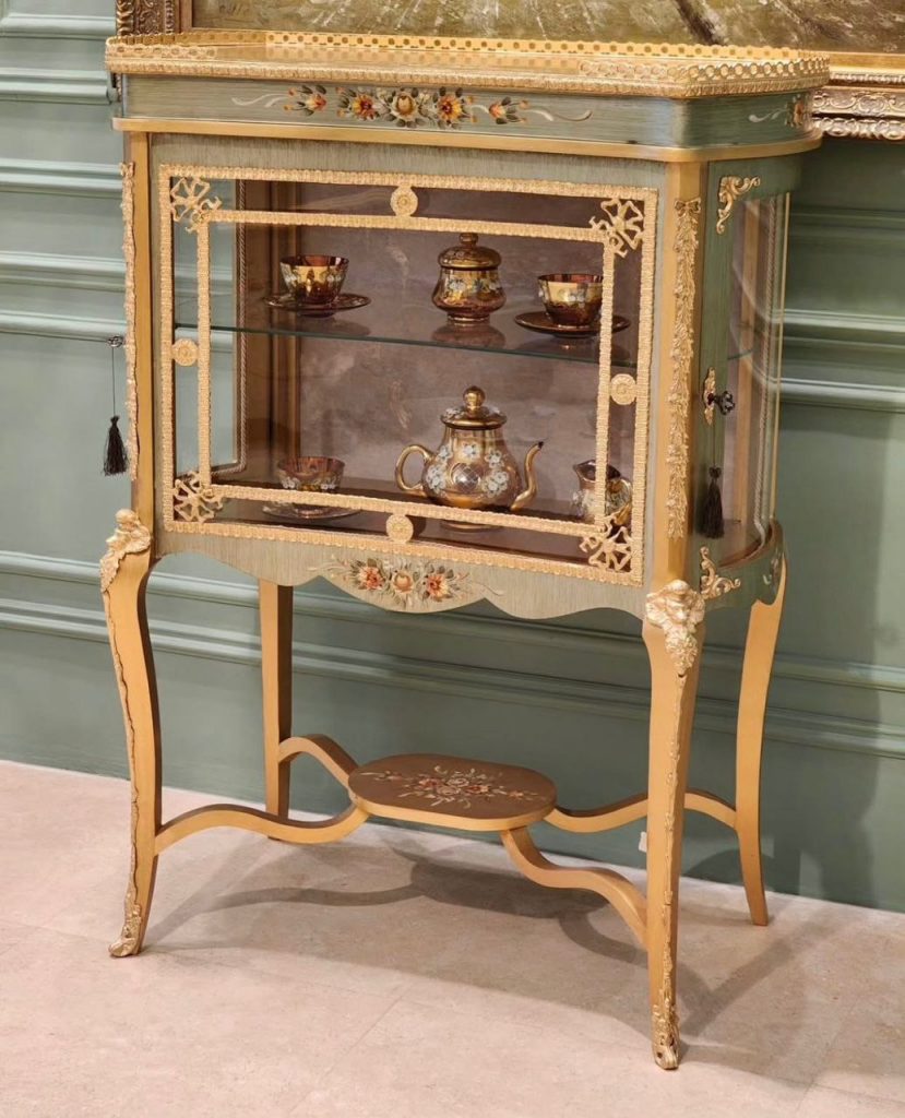 ویترین مانی کد 119 صنایع چوب رادین، محصولی لوکس از کیمیا کالکشن با طراحی کلاسیک، بدنه چوبی مرغوب، شیشه‌های شفاف و قفسه‌های کاربردی، انتخابی عالی برای نمایش ظروف کریستالی و لوازم دکوری در دکوراسیون لوکس.