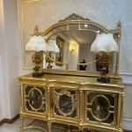 آینه کنسول نگینی از برند صنایع چوب رادین ساخته شده از چوب راش طبیعی با طراحی کلاسیک و نگین‌کاری زیبا، مناسب دکوراسیون لوکس منزل و سالن پذیرایی، دارای آینه کریستال شفاف و روکش براق در رنگ‌های طلایی و سفید صدفی.